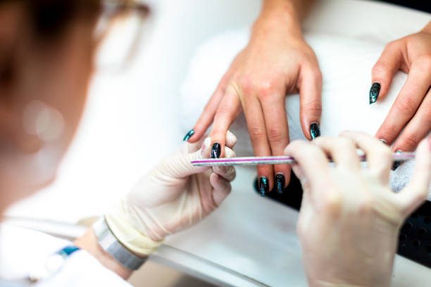 A nail file being used to tidy up a nail and remove cuticles during a manicure procedure.